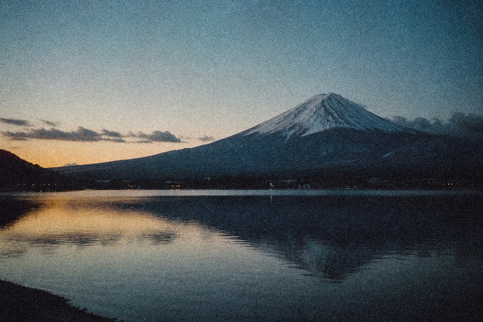 Mount Fuji at dawn across still water